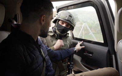 A masked soldier, identified as Meir, looks at the camera as he opens the door of the car where CNN correspondent Jeremy Diamond, left, sits detained in the northern West Bank village of Tayasir, March 26, 2026. (Screen capture: CNN)